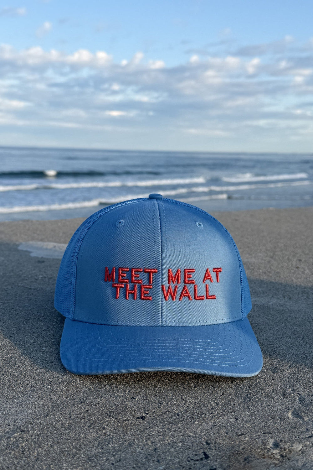 Meet Me At The Wall trucker hat in light blue on the North Beach seawall