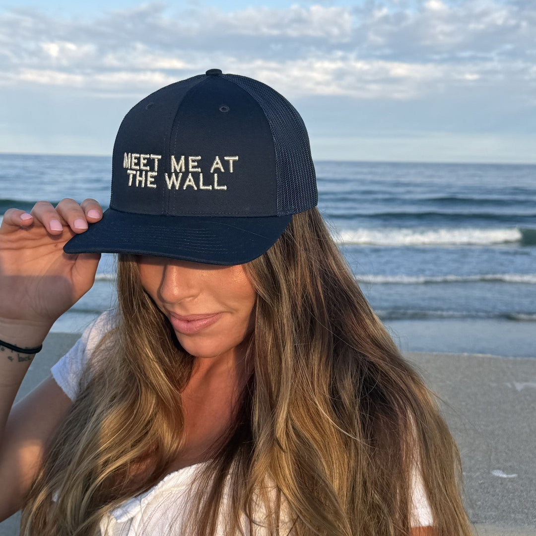 Meet Me At The Wall trucker hat in navy on model at the beach