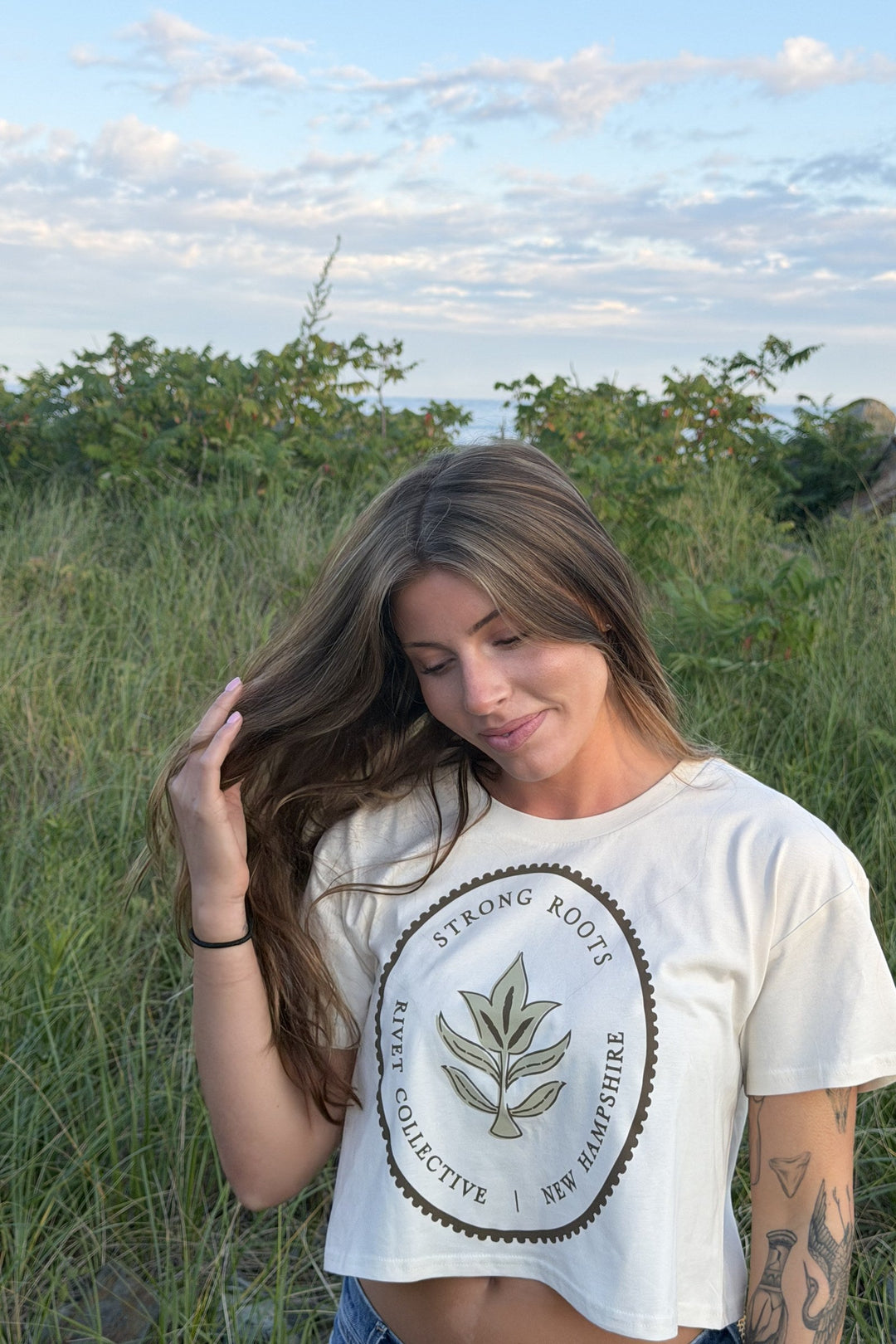 Strong Roots ecru crop tee on model in the beach grass