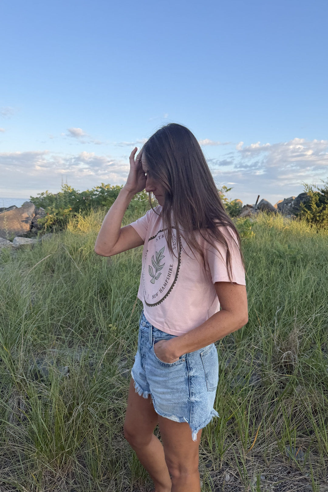 Strong Roots peach crop tee on model in the beach grass